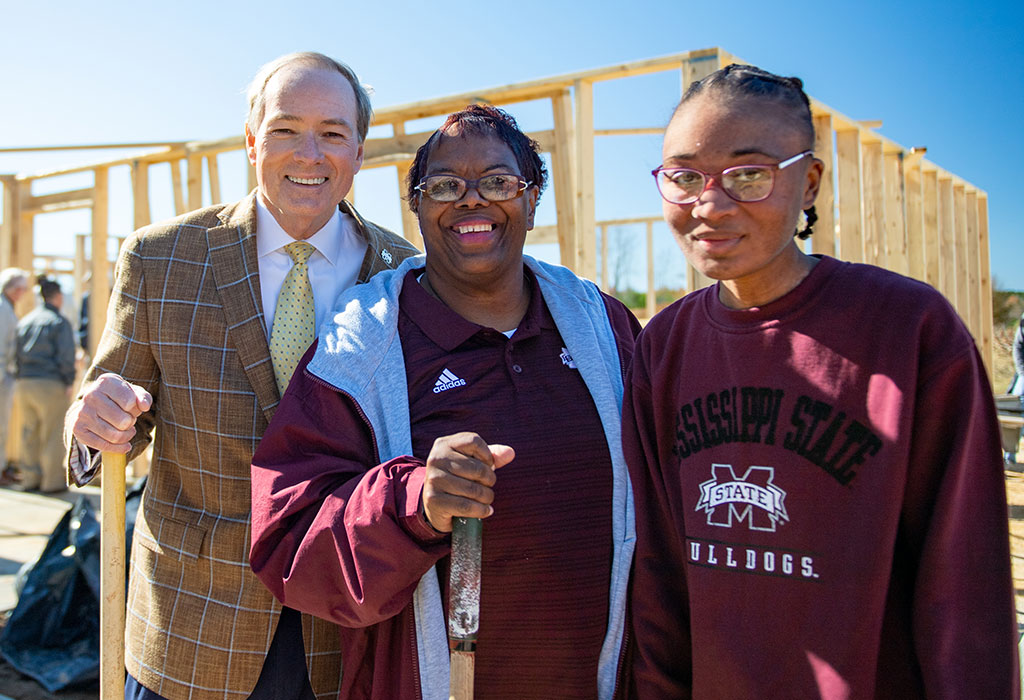 three people posing for a picture in front of a construction site.