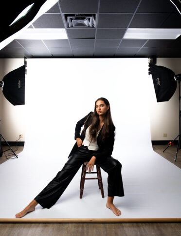 a woman sitting on a chair in a studio.