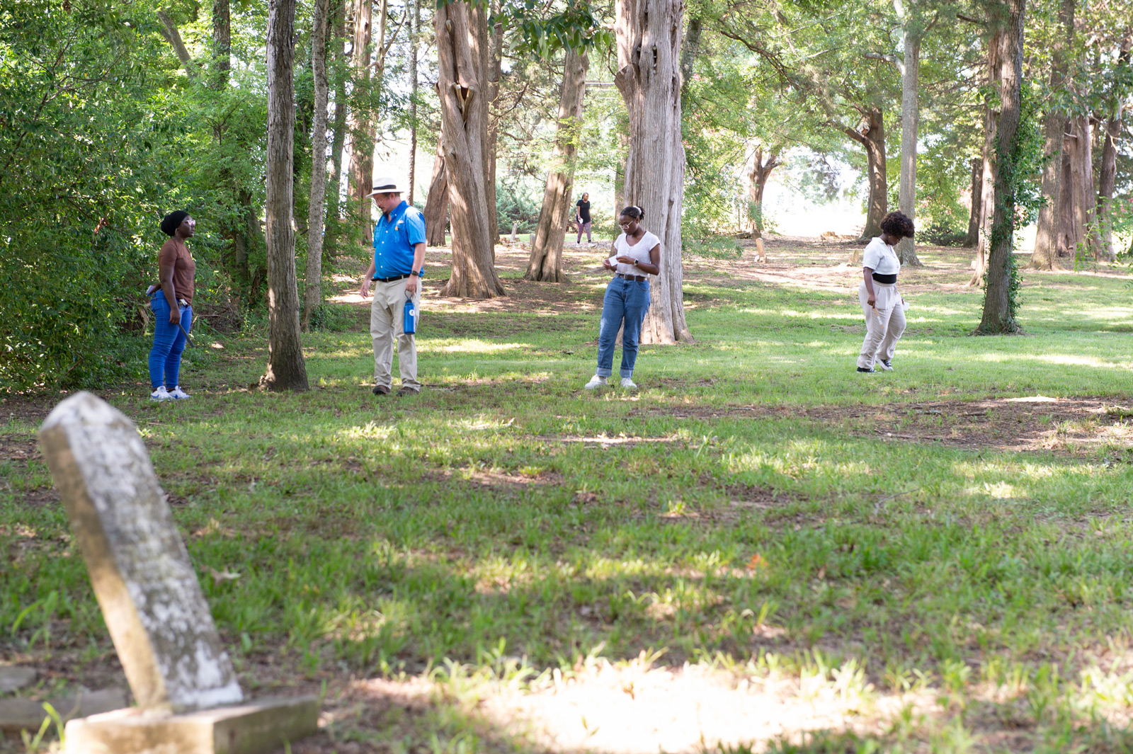 A group of people playing frisbee in a wooded area.