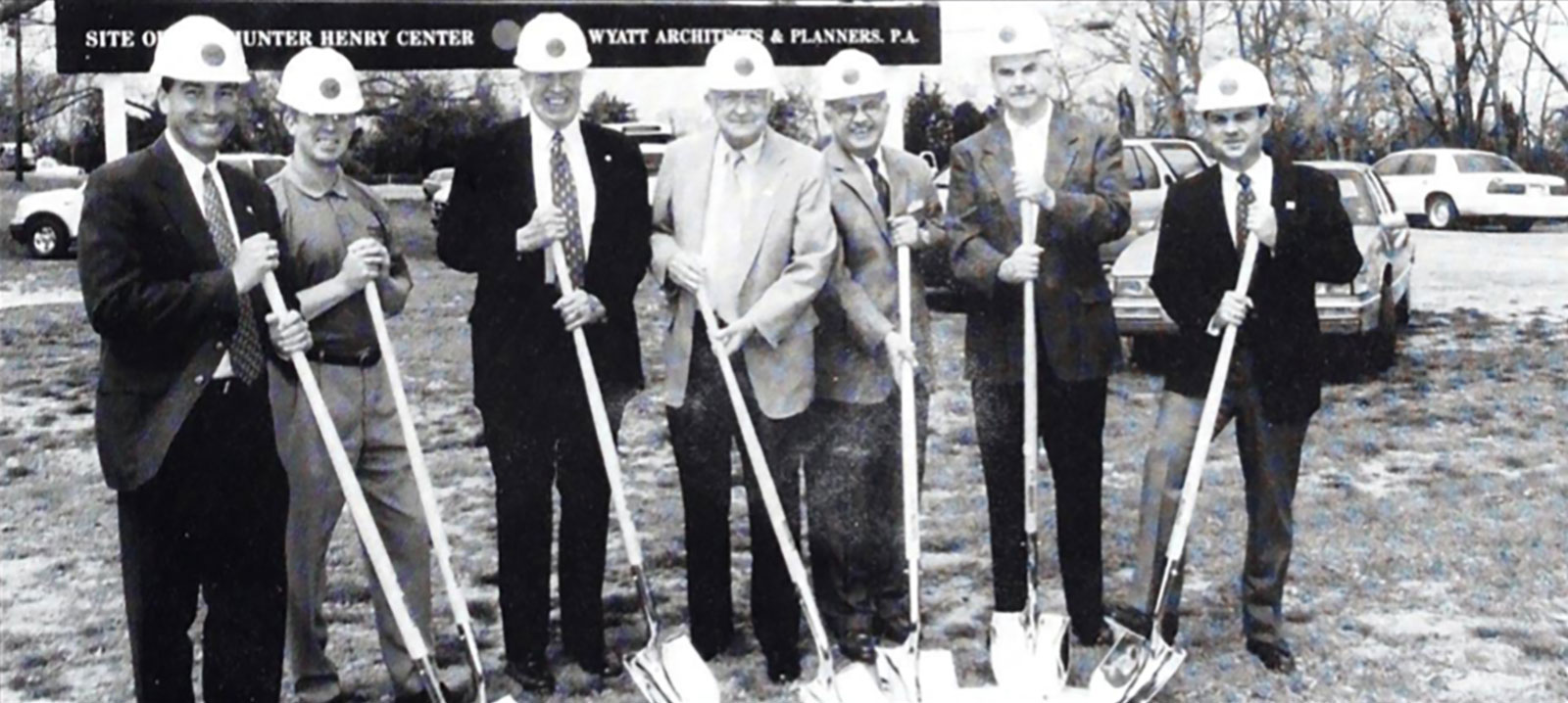 A group of men holding shovels in front of a building.