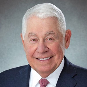 An older man in a suit and tie smiling.