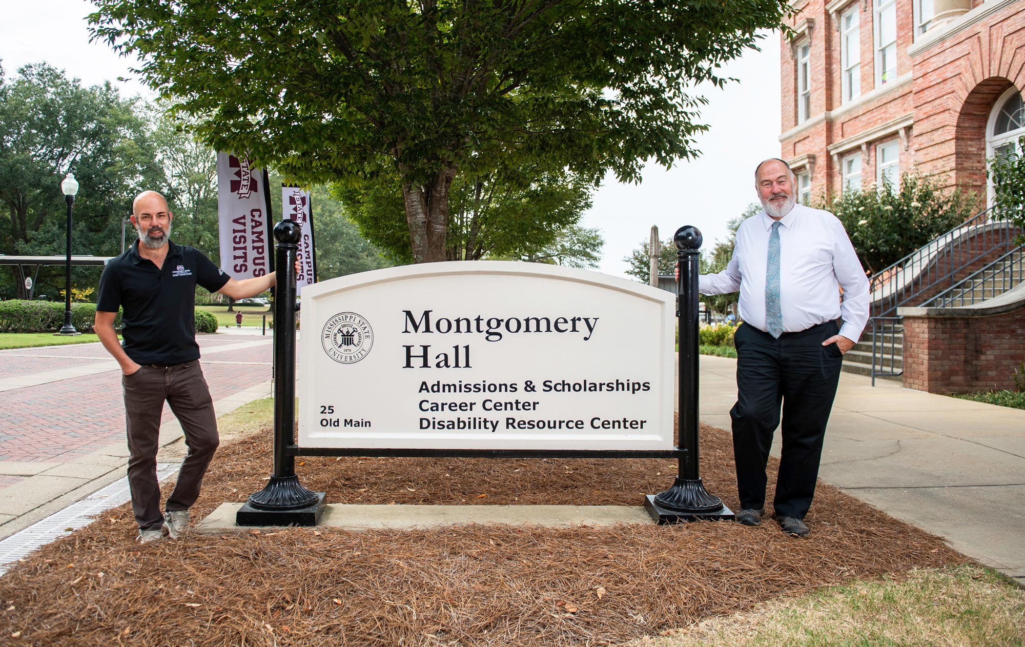 Two men standing in front of a sign that says mongomery hall.