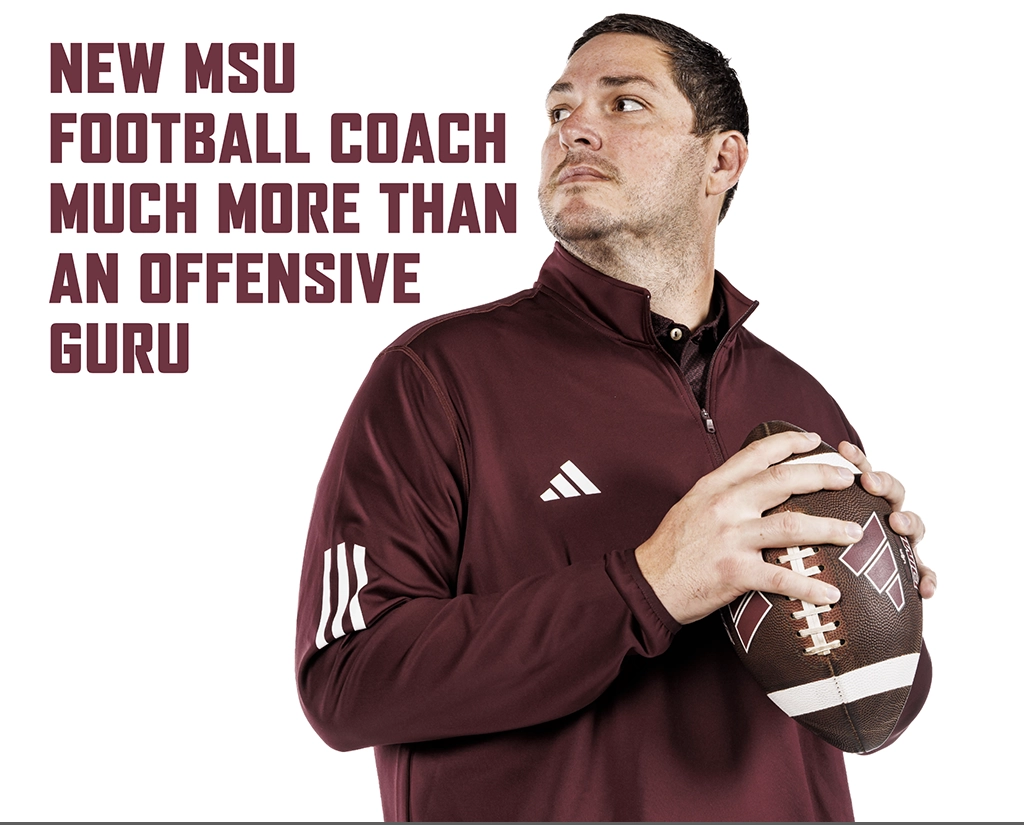 Coach Lebby looking over his shoulder while holding a football