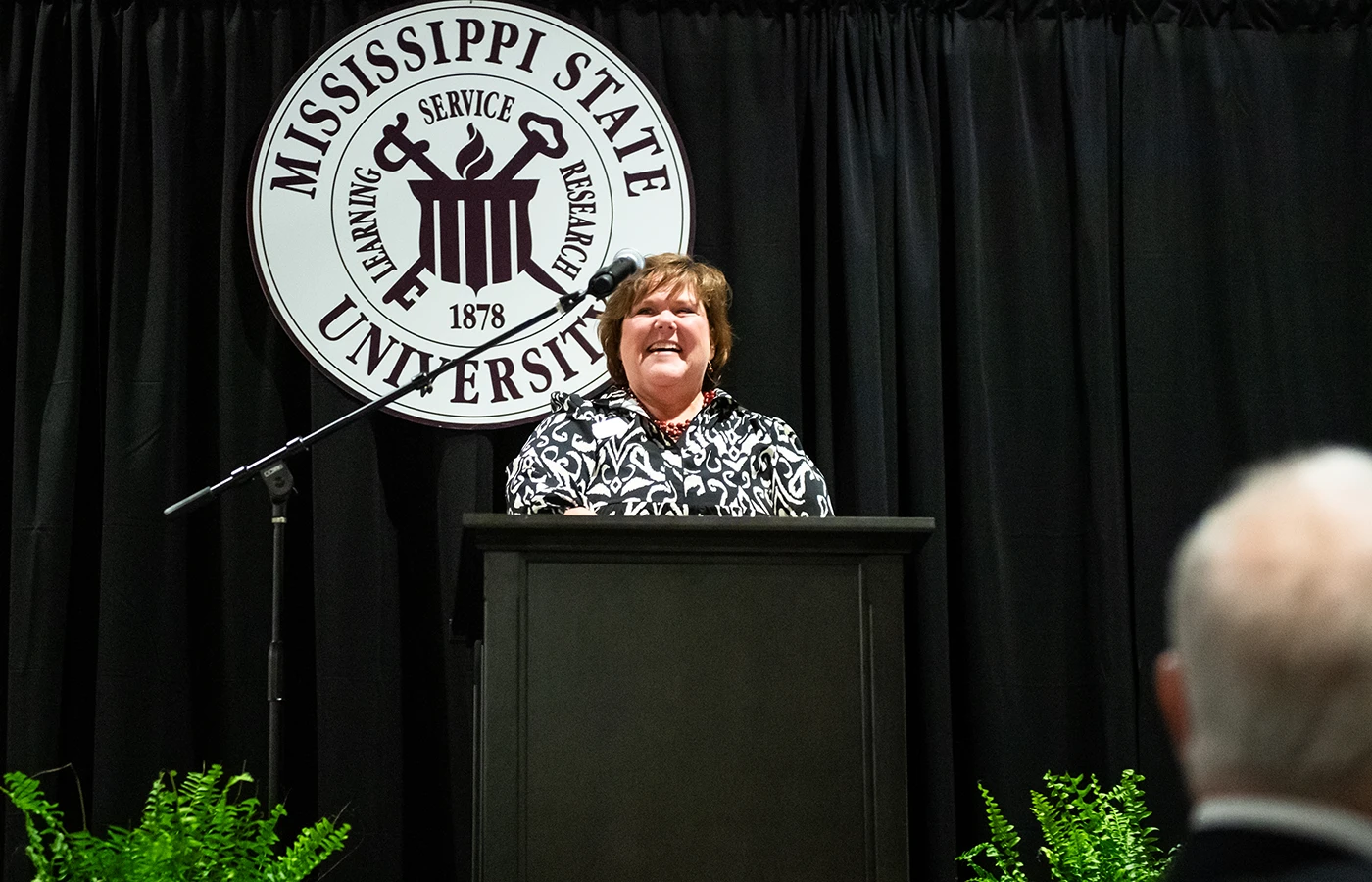 A person speaks at a podium with the Mississippi State University logo in the background.