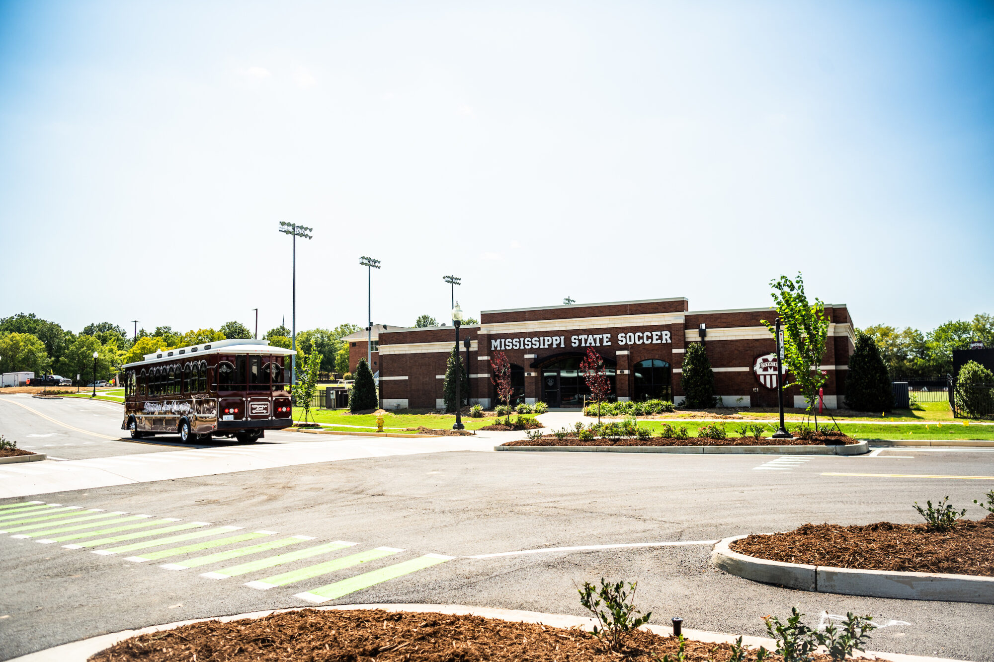 A trolley drives near the Mississippi State Soccer facility on a sunny day.