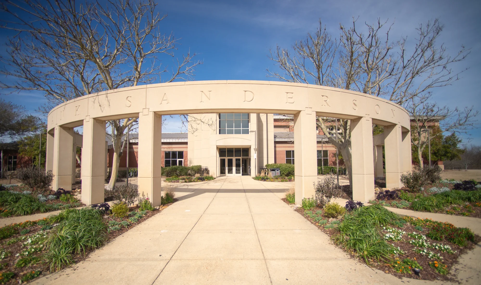 Exterior view of a building entrance with a circular archway and landscaped walkway.