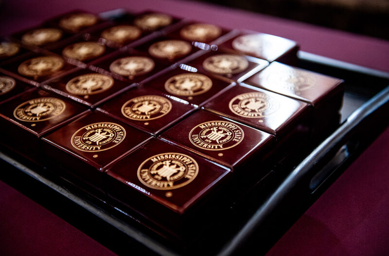 A tray of Mississippi State University branded boxes arranged in a grid pattern on a maroon tablecloth.