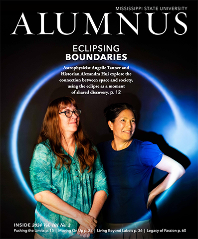 Two women stand closely together, smiling against a dark background. The magazine cover reads "Alumnus: Eclipsing Boundaries.