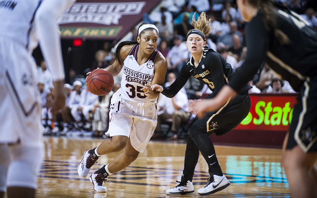 A Mississippi State basketball player dribbles the ball while being guarded by a Vanderbilt player during a game.