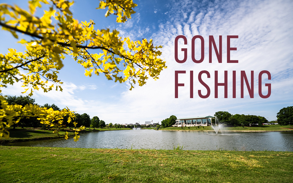 A pond with fountains, grassy banks, trees, and a branch with yellow flowers in the foreground. Large text reads "GONE FISHING.