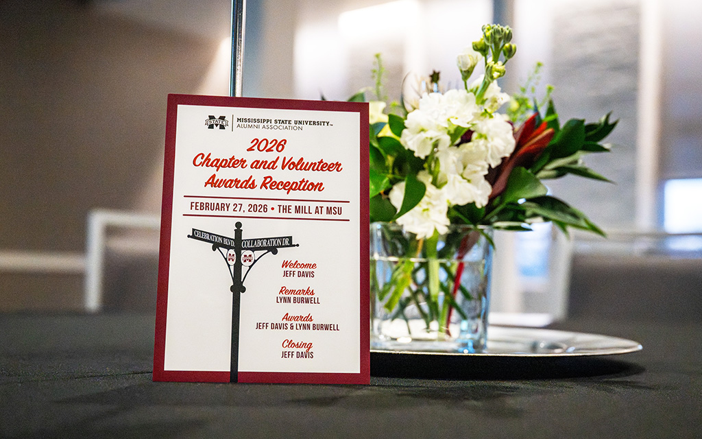 A program card for the 2026 Chapter and Volunteer Awards Reception at MSU stands on a table next to a floral arrangement.