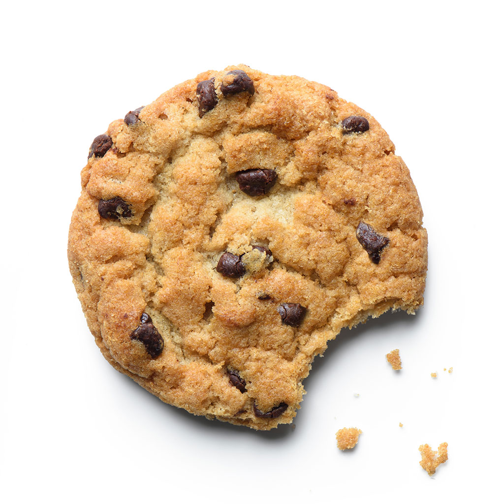 Chocolate chip cookie with a bite taken out and some crumbs on a white background.