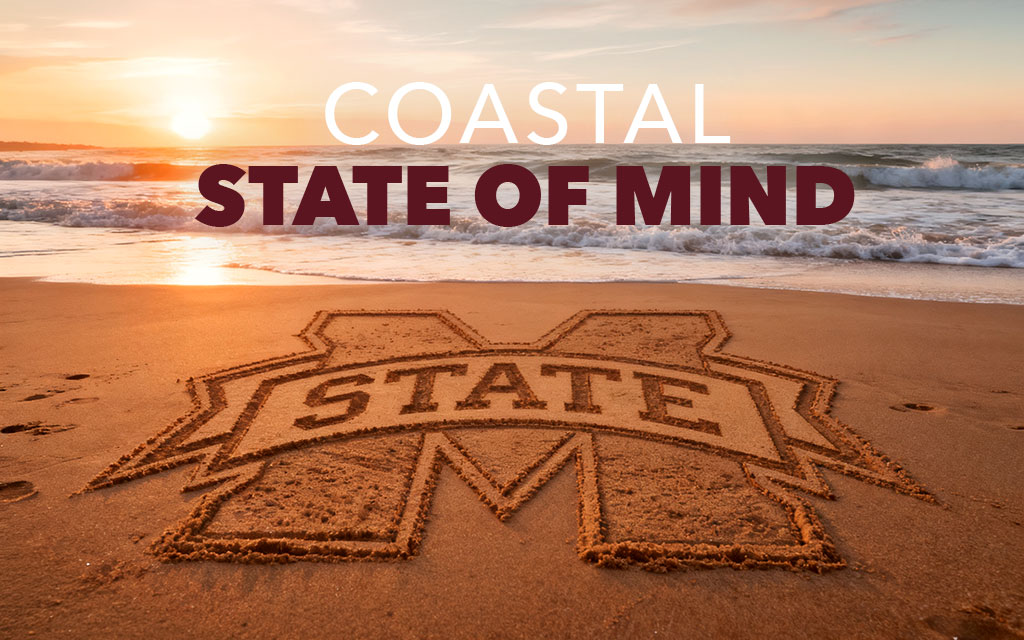 The Mississippi State University logo is drawn in sand on a beach at sunset with the text “Coastal State of Mind” above it.